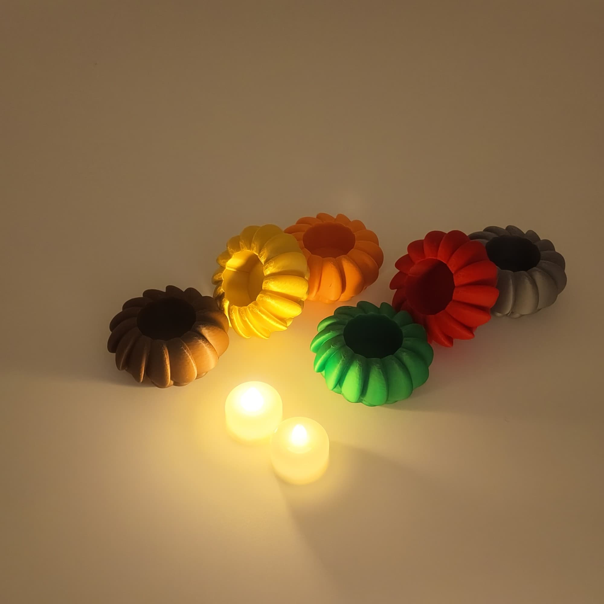 The six PetalGlow holders unlit, with two lit LED tealights in front
